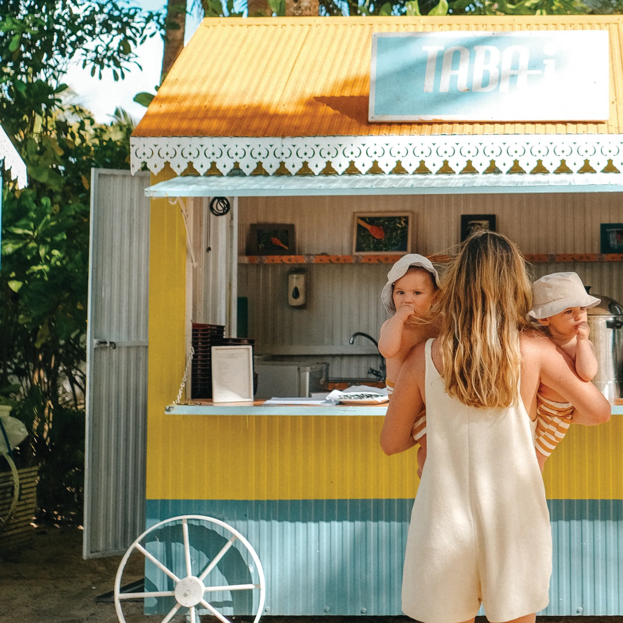 A family at the Attitude beach kiosk, a child on a parent's hip.